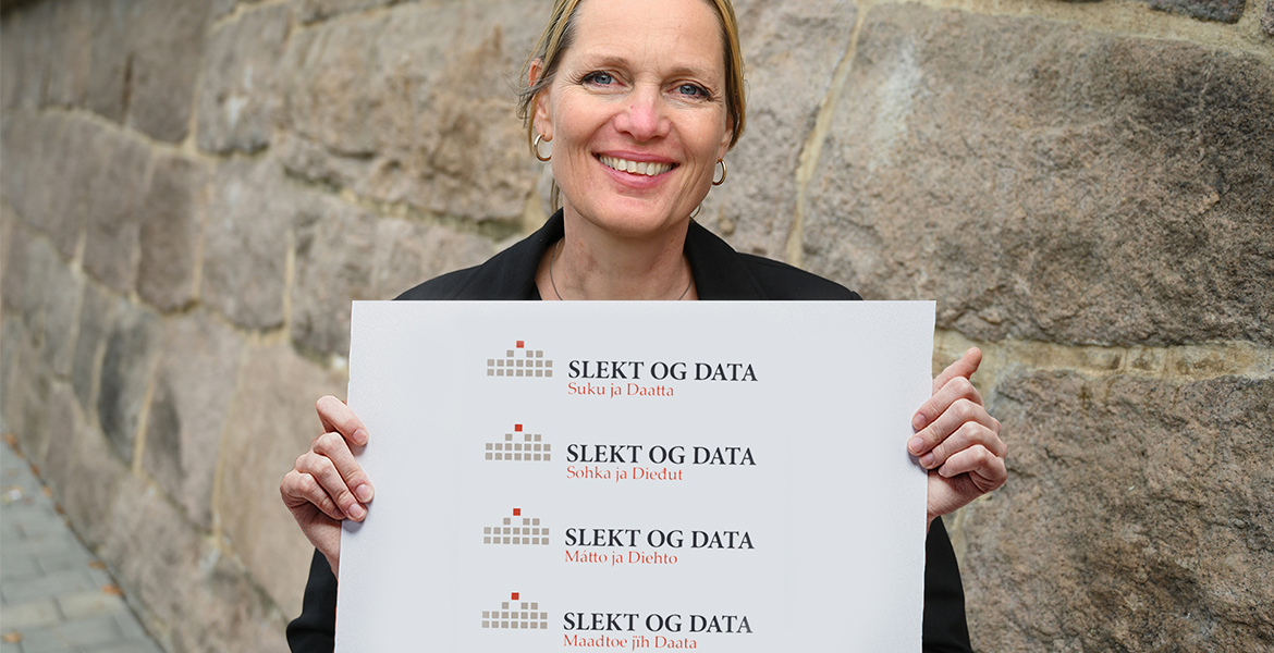 Generalsekretæren holder opp plakat med samiske og kvensk navn på Slekt og Data